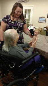 Activities Director Chrissy Brockway interacts with resident Patricia and her doll during a Harmony Club session.