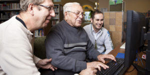Volunteers helping man with computer