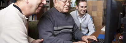 Volunteers helping man with computer