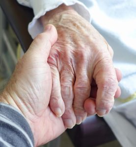 Younger hand holding an older one.