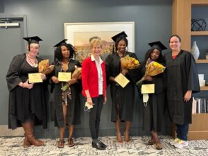 Five people in black graduation robes after earning CNA certification
