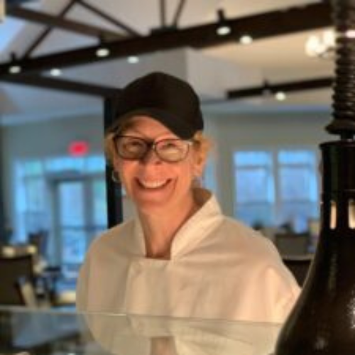 Woman in white chef's coat smiling